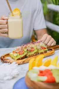 Breakfast at The Coco Café at Boardwalk Boutique Hotel Aruba with smoothie, avocado toast, and fresh fruit.