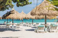 Boardwalk Boutique Hotel Aruba beach area with palapas and lounge chairs on the white sand.