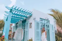 Guest walking onto the deck of a light blue Caribbean casita surrounded by tropical plants at Boardwalk Boutique Hotel Aruba.