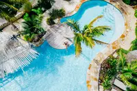 Resort pool at Boardwalk Boutique Hotel Aruba surrounded by palm trees and tropical gardens, with lounge areas around the water.