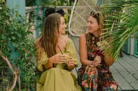 Two women chatting in a tropical garden seating area beside a casita porch at Boardwalk Boutique Hotel Aruba.