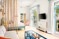 Coco Casita living area at Boardwalk Boutique Hotel Aruba with bright seating, TV, and sliding doors to the terrace.