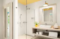 Modern One-Bedroom Casita bathroom at Boardwalk Boutique Hotel Aruba with glass walk-in shower and vanity.