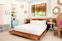 Palapa Lodge bedroom at Boardwalk Boutique Hotel Aruba with king bed, tropical decor, and kitchenette.