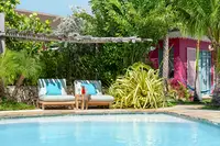 Pool at Boardwalk Boutique Hotel Aruba with daybeds and lush greenery.