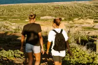 o people hiking on a rugged Aruba trail with ocean views (near Boardwalk Boutique Hotel Aruba).