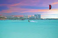 Kitesurfer on turquoise water off Palm Beach, Aruba at sunset.