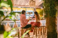 Couple enjoying a romantic dinner at a bar table in a tropical restaurant setting at Boardwalk Boutique Hotel Aruba.