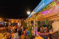 Crowds at the Authentico Aruba Culinary Festival at night with food stalls and lights in Oranjestad, Aruba.