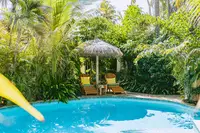 Swimming pool at Boardwalk Boutique Hotel Aruba surrounded by lush gardens and palm trees.