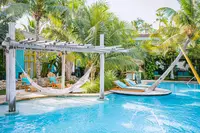 Pool with hammocks at Boardwalk Boutique Hotel Aruba in a tropical garden setting.