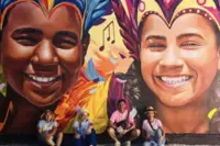 Guests in front of a colorful street art mural in Aruba, featured in Armando Goedgedrag’s Artist in Residence story at Boardwalk Boutique Hotel Aruba.