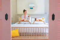 Guest sitting on a bed with a breakfast tray in a bright, cozy bedroom at Boardwalk Boutique Hotel Aruba.