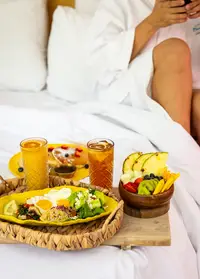 Breakfast in bed at Boardwalk Boutique Hotel Aruba with fresh fruit, pastries, and juices.