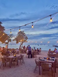 Beachfront dining at Moomba in Aruba at sunset, with string lights and ocean views.