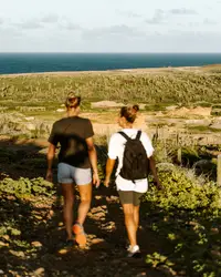o people hiking on a rugged Aruba trail with ocean views (near Boardwalk Boutique Hotel Aruba).