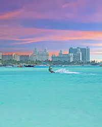 Kitesurfer on turquoise water off Palm Beach, Aruba at sunset.