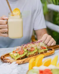 Breakfast at The Coco Café at Boardwalk Boutique Hotel Aruba with smoothie, avocado toast, and fresh fruit.